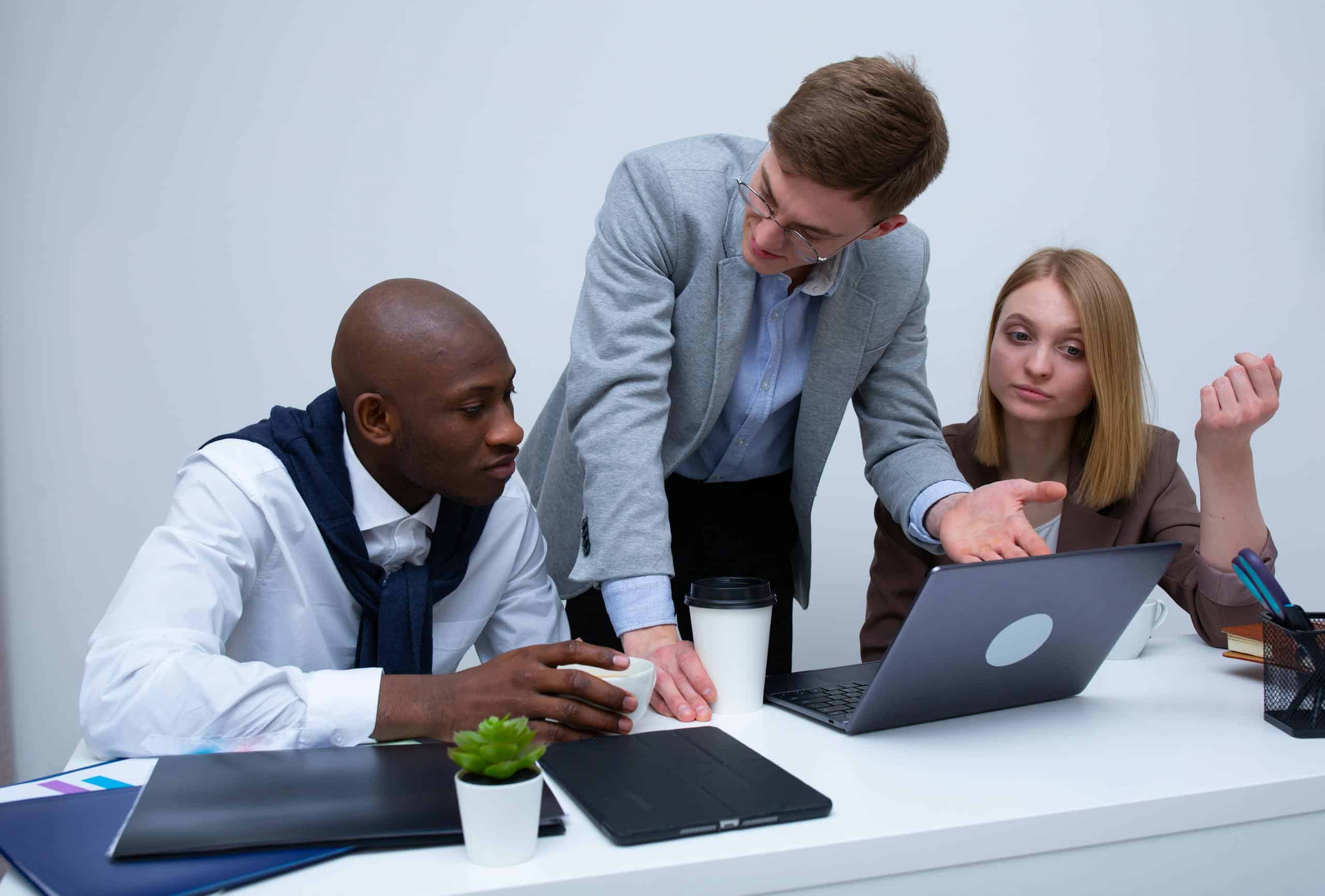 Three professionals engage in a lively business discussion at a modern office desk, focusing on teamwork.